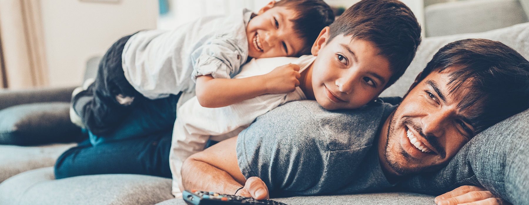 father with two sons laying down on the couch